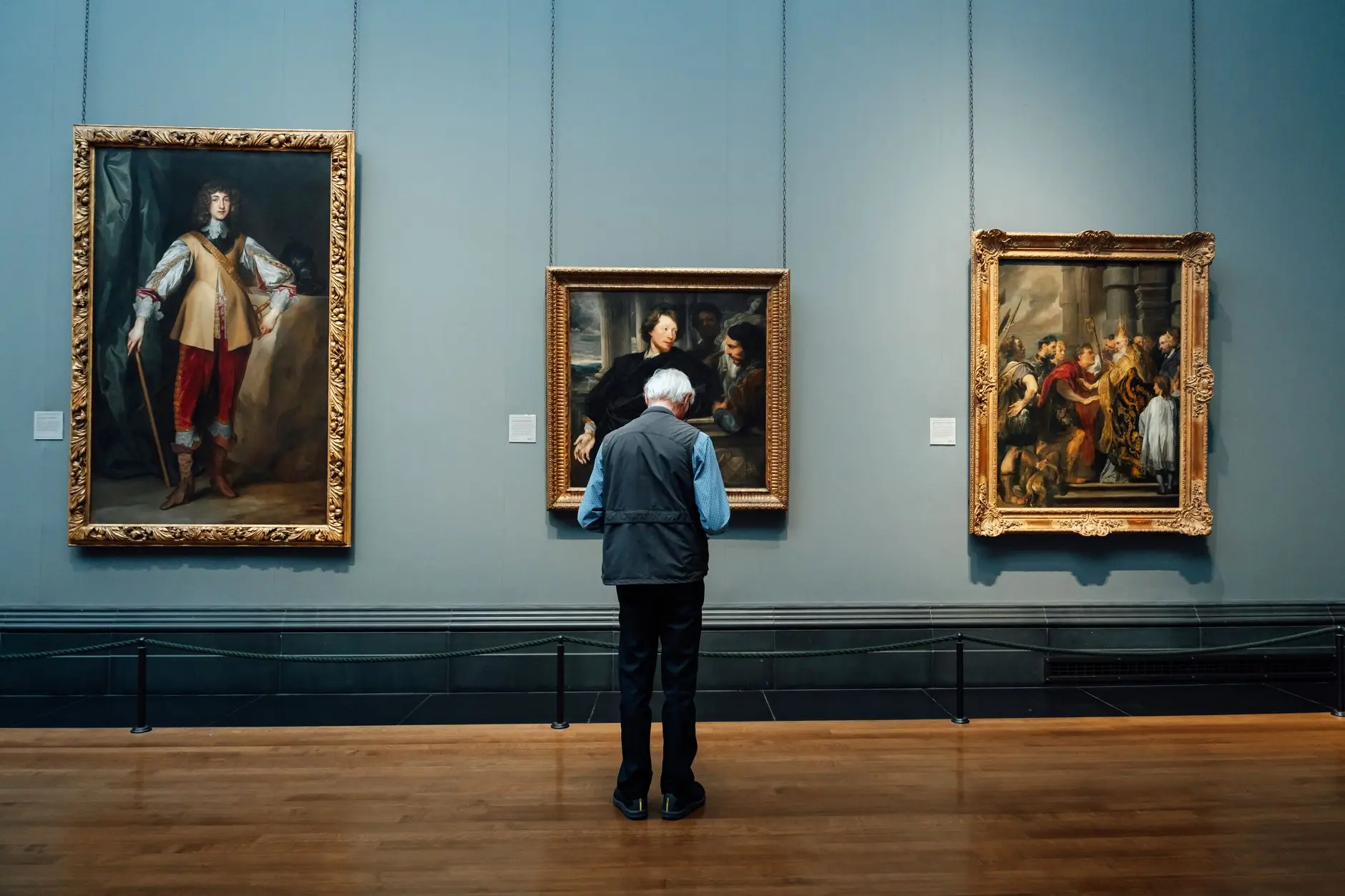 A visitor studying classic paintings on a gallery wall