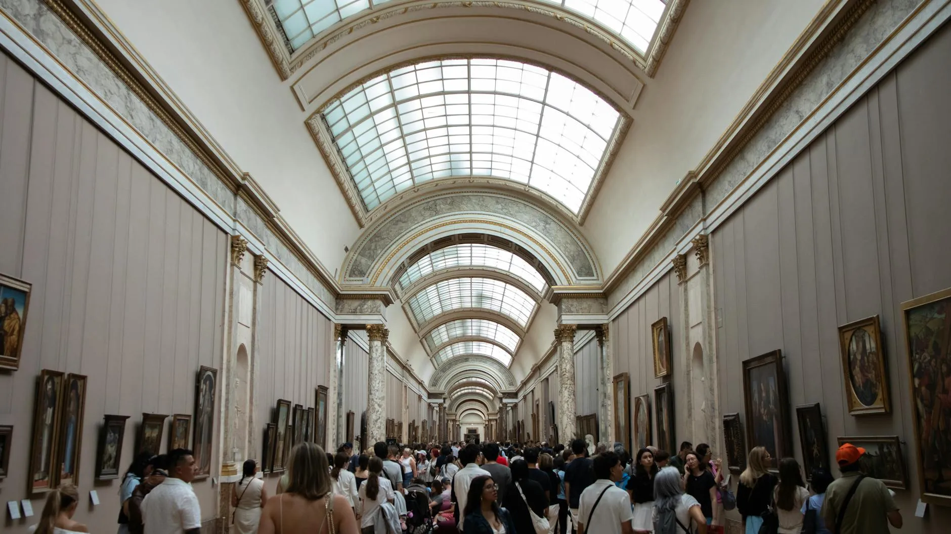 Museum gallery corridor with visitors exploring extensive art exhibits