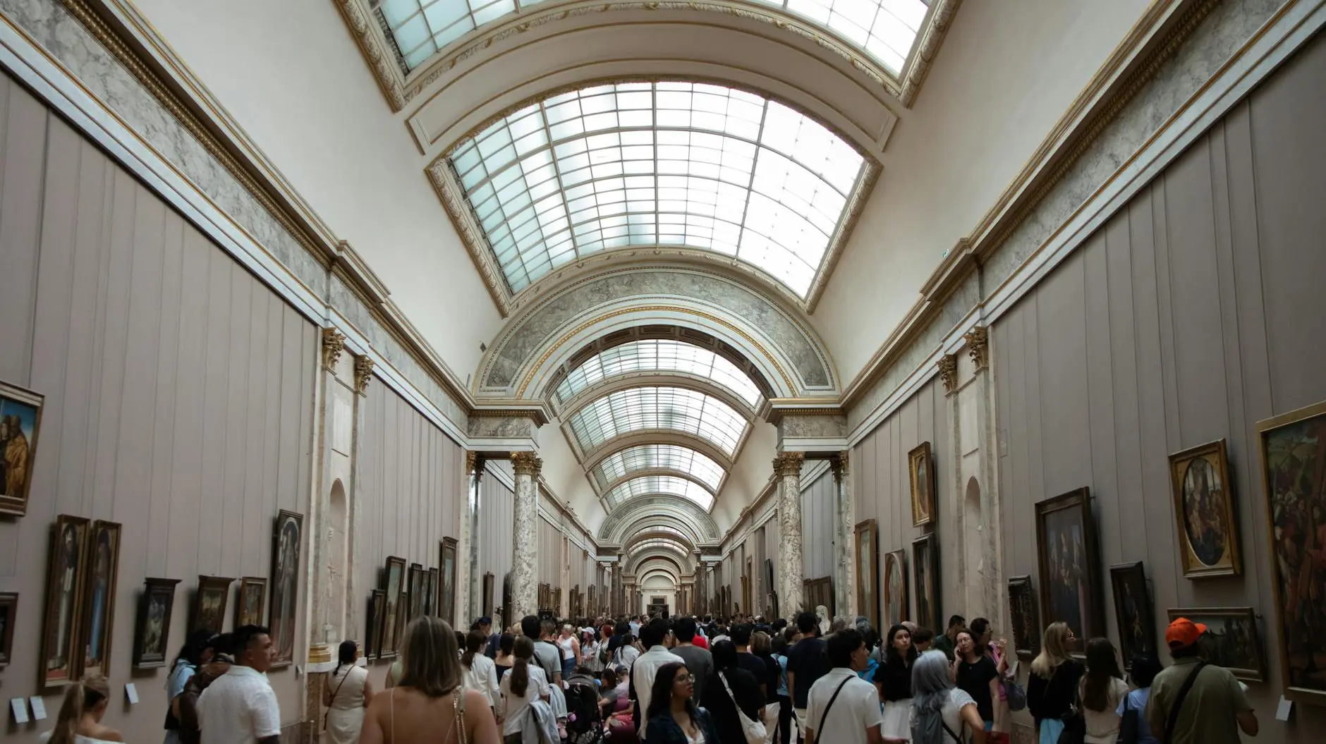 Museum gallery corridor with visitors exploring extensive art exhibits