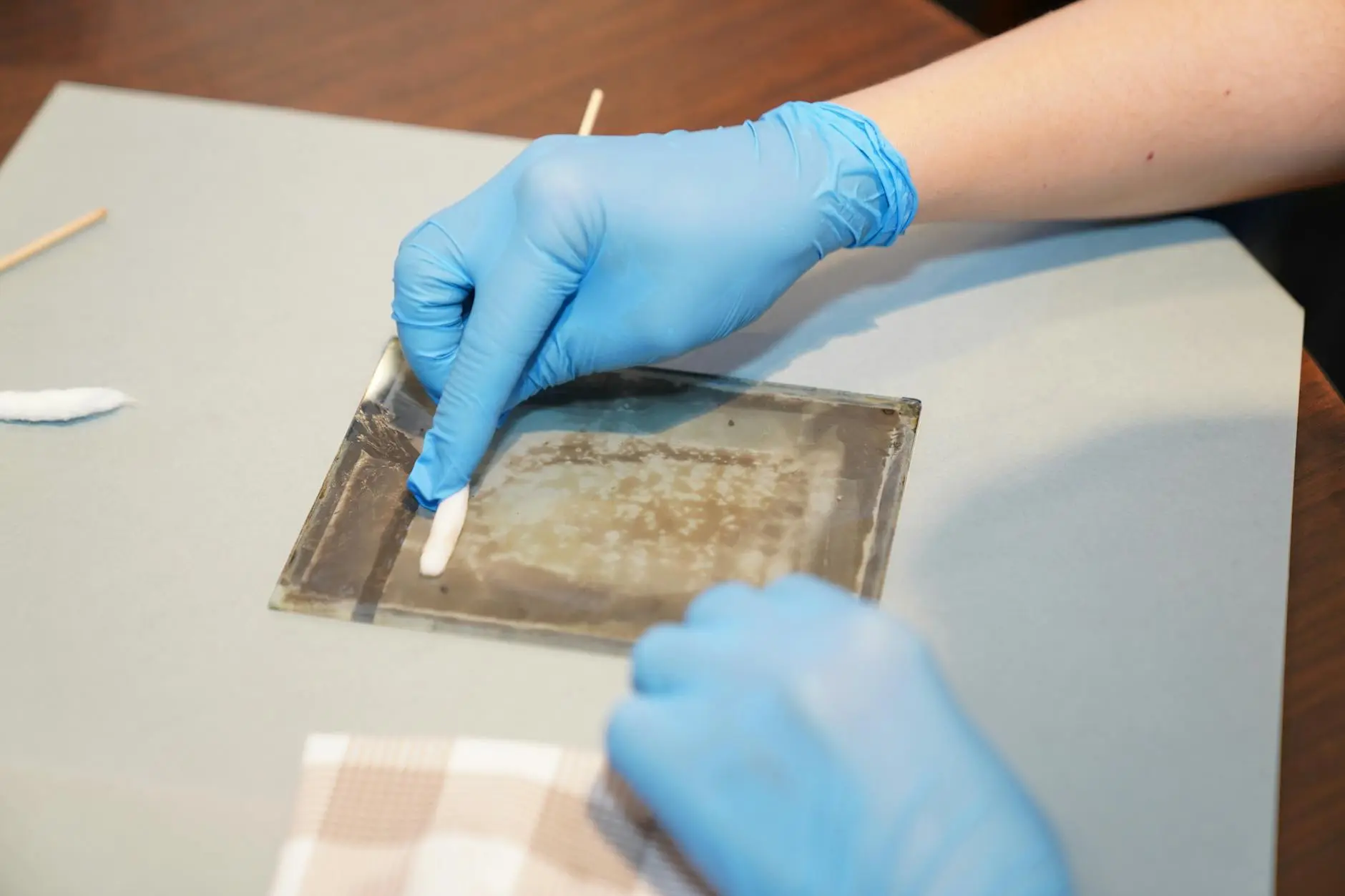 Gloved hands carefully handling and restoring vintage artwork