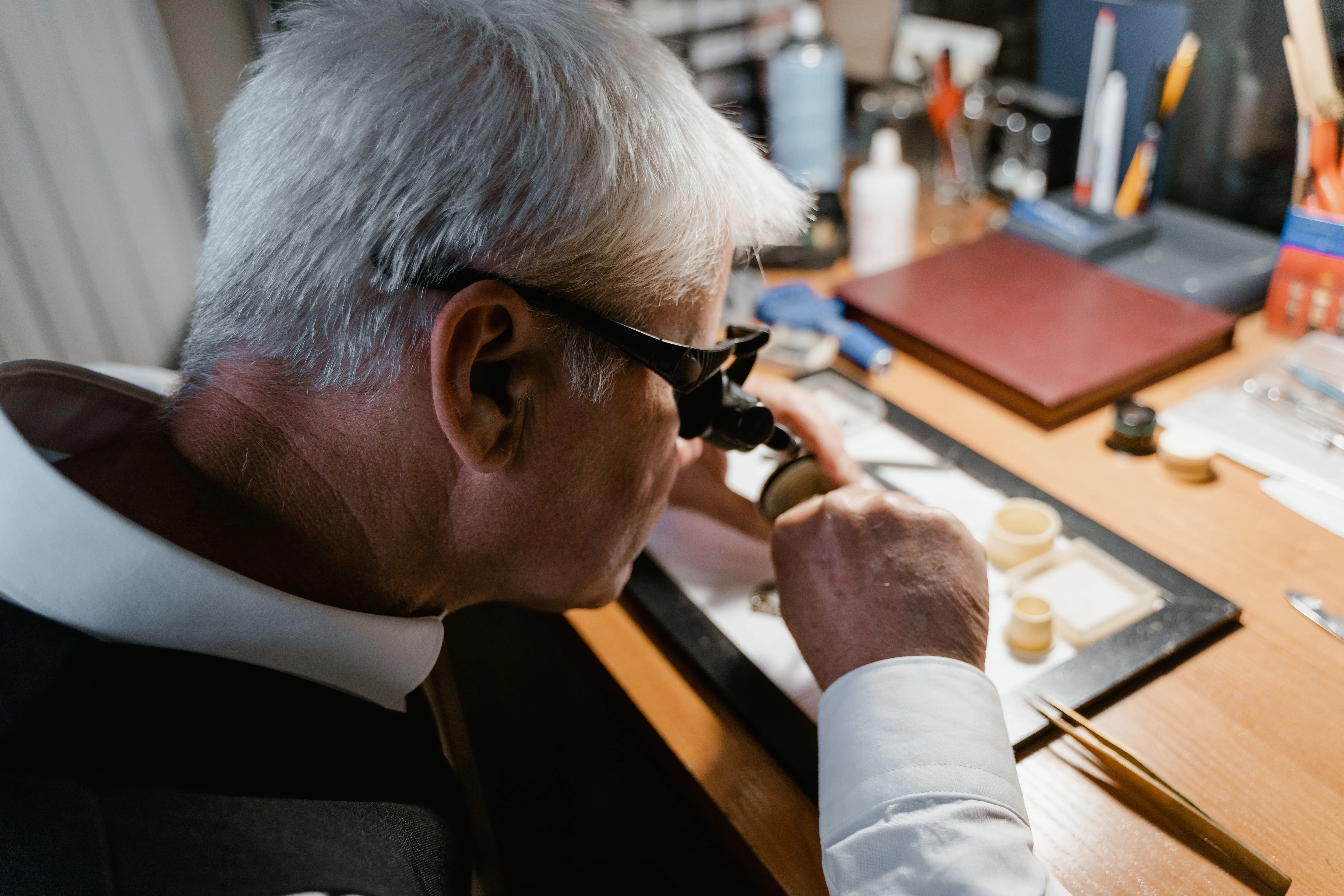 A specialist examining a timepiece through a loupe at a workbench
